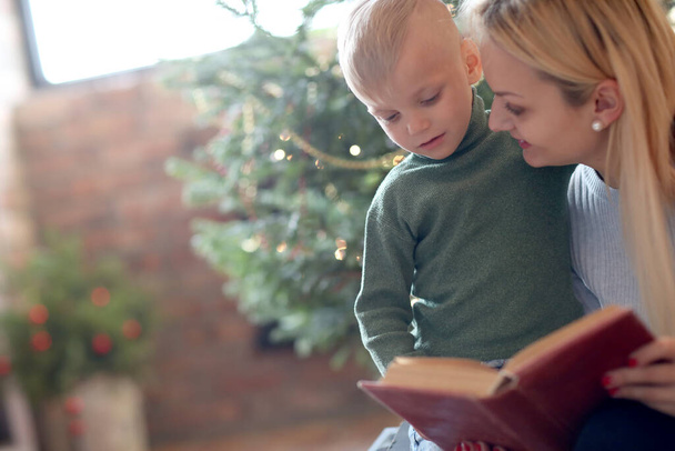 Nochebuena. Madre y su hijo junto al árbol de Navidad - Foto, imagen