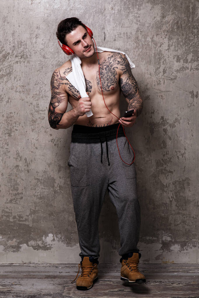 Tatuoitu kaveri punaisella kuulokkeella
 - Valokuva, kuva