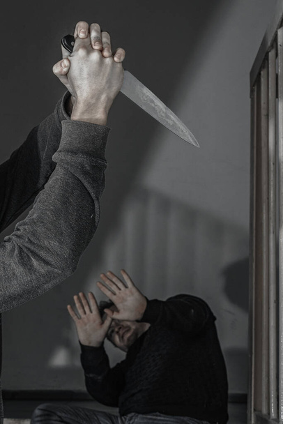 Een man met een mes probeert een man te doden op de overloop. onderwerpen van geweld en moord. dief, moordenaar, verkrachter, maniak, beroving - Foto, afbeelding