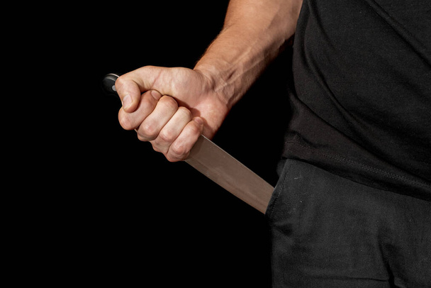Man's hand holds a knife on black background. topics of violence and murder. thief, killer, rapist, maniac - 写真・画像