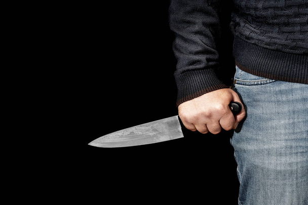 Die Hand des Mannes hält ein Messer auf schwarzem Hintergrund. Themen von Gewalt und Mord. Dieb, Killer, Vergewaltiger, Wahnsinniger - Foto, Bild