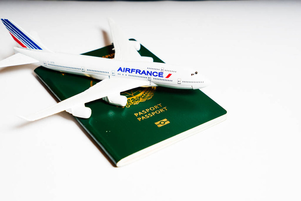 Kleines Spielzeugflugzeug auf grünem Reisepass auf weißem Hintergrund. - Foto, Bild