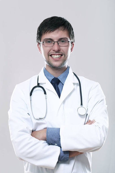 Fiatal mosolygó orvos sztetoszkóp, mint szürke háttér - Fotó, kép