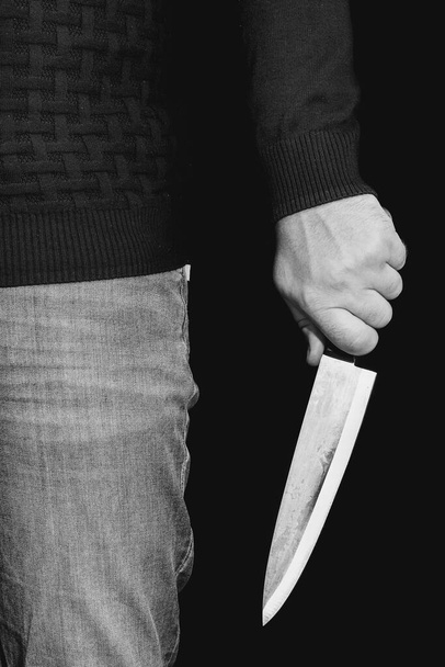 Man's hand holds a knife. topics of violence and murder. thief, killer, rapist, maniac. black and white photo - Photo, Image