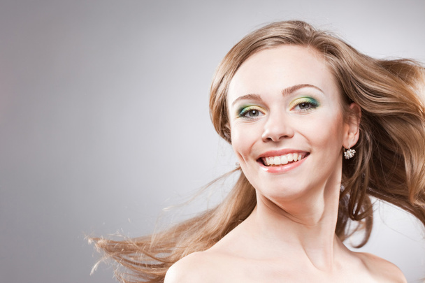 Happy smiling young woman with her hair blowing - Photo, Image