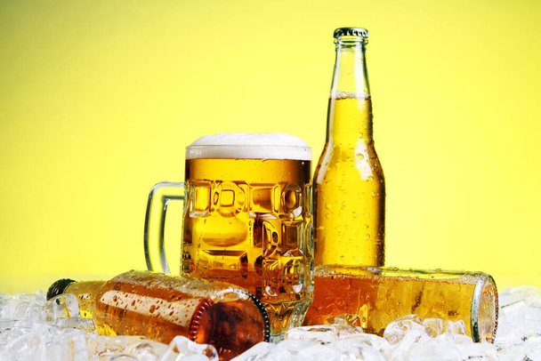 Bottiglie e bicchiere di birra con schiuma su sfondo giallo
 - Foto, immagini