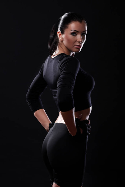 Beautiful fitness girl with sexy body over black background - Foto, afbeelding