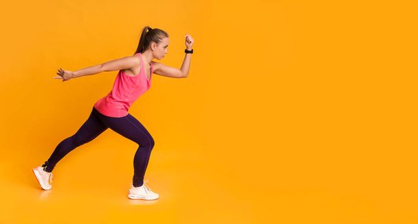 Motivierte junge Frau in Sportkleidung läuft über gelben Hintergrund - Foto, Bild