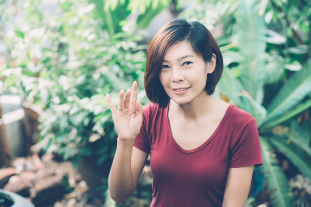 Schönes Porträt junge asiatische Frau lächelt winkende Hand im Garten zu Hause, Freundliches Mädchen und Ausdruck positiver Emotionen, Hallo und Gruß, eine Person, glückliche Frau aufgeregt und fröhlich. - Foto, Bild