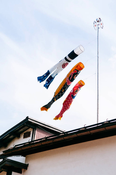 Banderas Koinobori - Colorida bandera de peces de la carpa que se mueve en el viento en el techo de la casa local, símbolo del día de los niños japoneses - Foto, Imagen