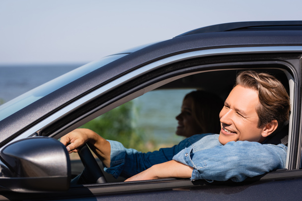 Selective focus of man looking away while driving auto near wife  - Φωτογραφία, εικόνα