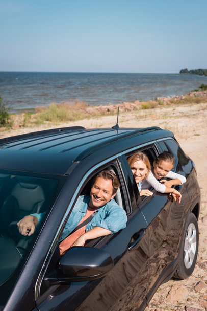 Мужчина за рулем автомобиля рядом с семьей во время отпуска на море  - Фото, изображение