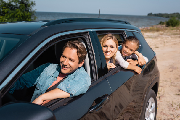Selective focus of family traveling in car on seaside at daytime  - Photo, Image