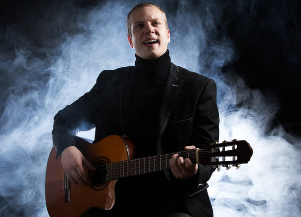 Music. Musician in black suit with a guitar - Photo, Image