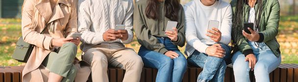 Close up of friends sitting in row and using smartphones - Zdjęcie, obraz