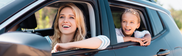 Panoramic shot of excited woman looking away while traveling with daughter in car  - Photo, image