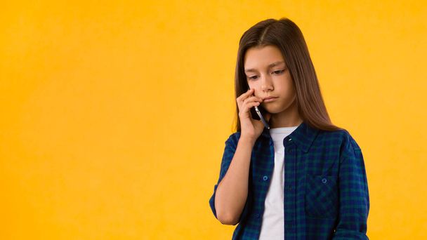 Молодая грустная девушка разговаривает по телефону - Фото, изображение