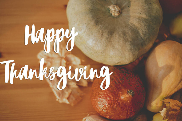 Joyeux Thanksgiving carte de vœux. Texte de Happy Thanksgiving écrit à la main sur fond de citrouilles, feuilles d'automne, noix, légumes de récolte sur table rustique en bois. - Photo, image