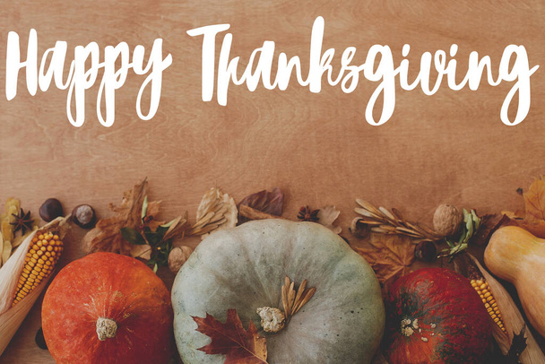 Joyeux Thanksgiving carte de vœux. Texte de Happy Thanksgiving écrit à la main sur fond de citrouilles, feuilles d'automne, noix, légumes de récolte sur bois rustique, pose plate. - Photo, image