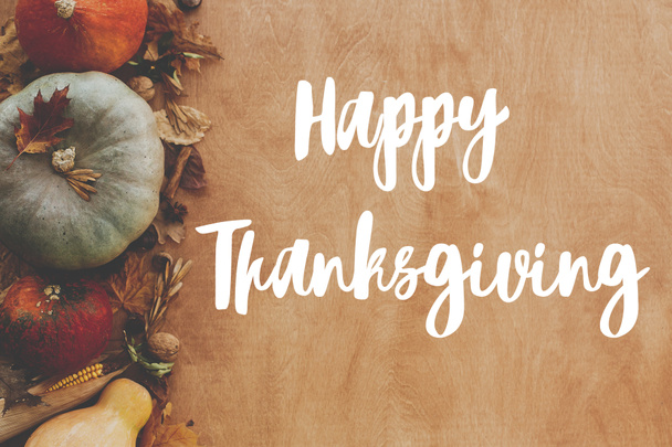 Handgeschriebener Happy Thanksgiving Text auf Hintergrund von Kürbissen, Herbstblättern, Nüssen, Gemüse ernten auf rustikalem Holz, flach gelegt. Glückwunschkarte zum Erntedank. - Foto, Bild