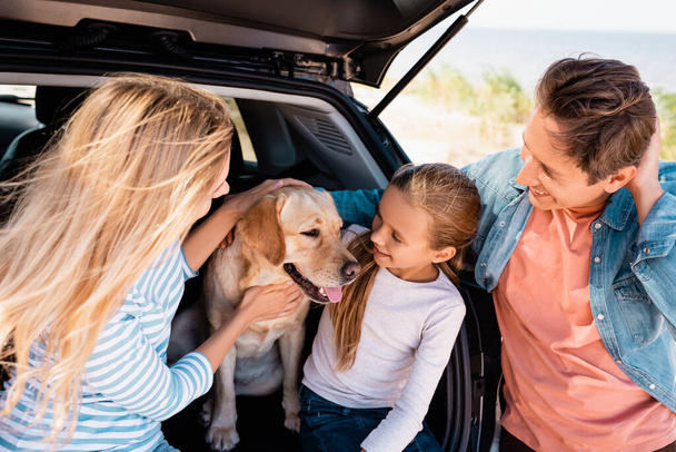 Selective focus of family looking at golden retriever in car truck outdoors  - Fotó, kép
