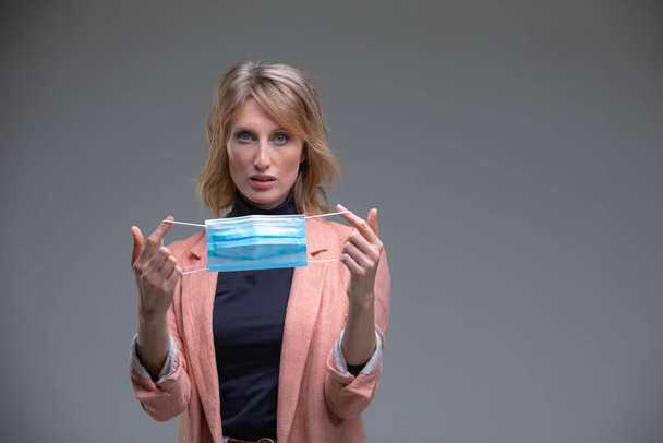 Blond woman hold her surgical mask - Foto, Bild