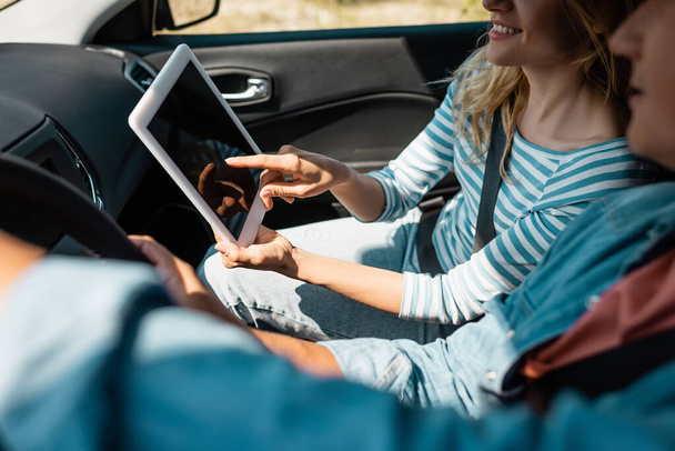 Vue recadrée de la femme pointant vers tablette numérique pendant que le mari conduisait une voiture  - Photo, image