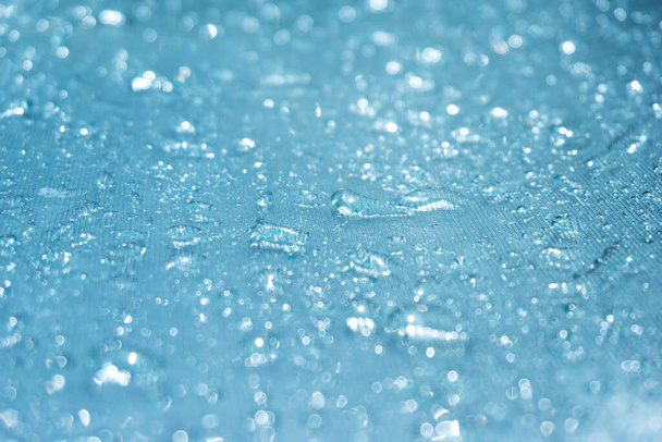 Gocce di pioggia sullo sfondo di vetro blu bokeh, gocce di pioggia lucide su una superficie di vetro, gocce d'acqua in un primo piano della piscina - Foto, immagini