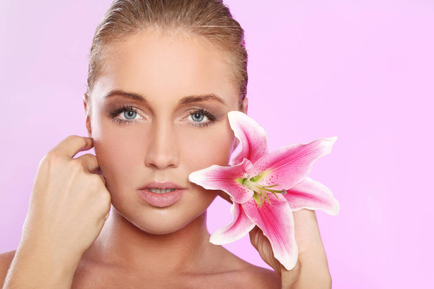 Mulher jovem e bonita com flor de lírio sobre fundo rosa
  - Foto, Imagem