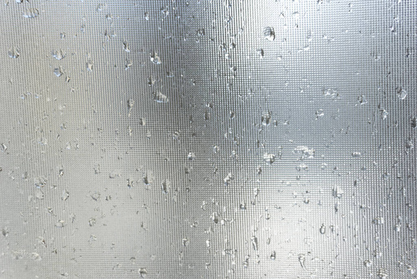 灰色のガラスの背景に雨が降り、灰色のガラスの表面に雨が降ります - 写真・画像