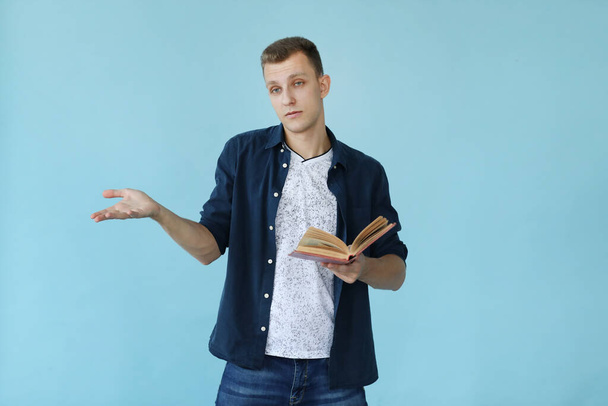 Knappe man met boek op een blauwe achtergrond - Foto, afbeelding