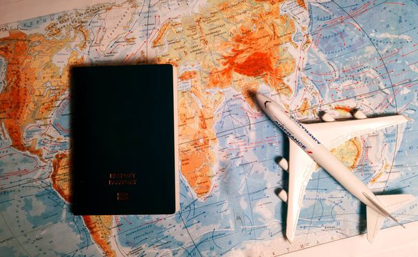 Sulje valkoinen lelu lentokone ja passi maailmankartalla taustalla. Matkailu ja liikekonsepti - Valokuva, kuva