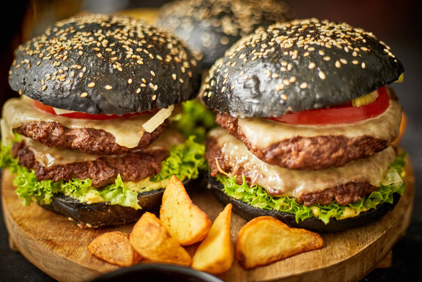 Apetyczne czarne hamburgery i smażone ziemniaki - Zdjęcie, obraz