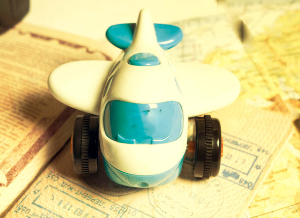 Piccolo aereo giocattolo blu che giace sulla pagina del passaporto con timbri di visto nella mappa parola, tonica - Foto, immagini