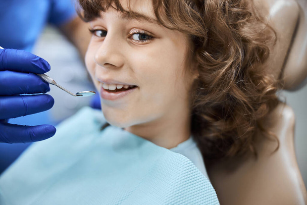 Diş hekiminin ofisinde gülümseyen pozitif görünüşlü bir çocuk. - Fotoğraf, Görsel
