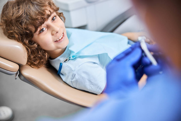 Uśmiechnięty dzieciak na krześle gotowy do leczenia stomatologicznego - Zdjęcie, obraz