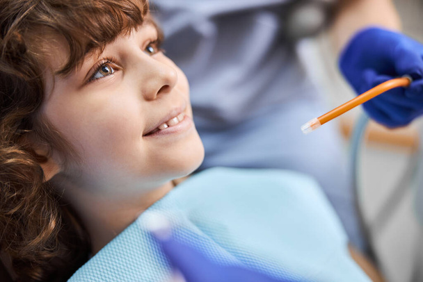Niño alegre durante un chequeo dental con aspecto positivo - Foto, imagen