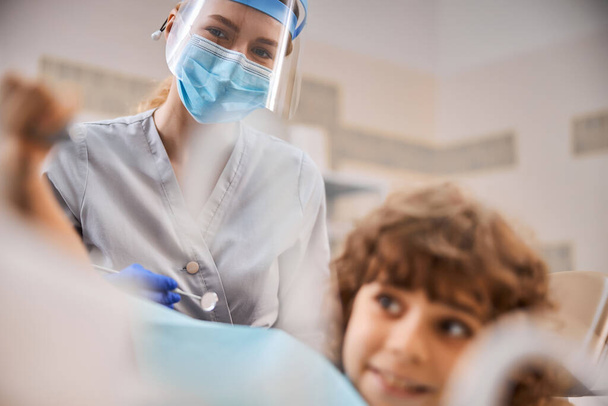 Уважний дитячий стоматолог піклується про молодого пацієнта
 - Фото, зображення