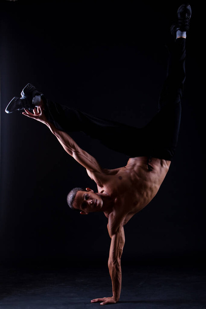 Young and muscular hispanic dancer over black background - Фото, изображение