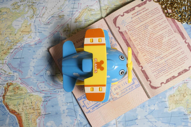 Маленький голубой игрушечный самолет, лежащий на странице паспорта с визовыми штампами на карте слов, тонизированный - Фото, изображение