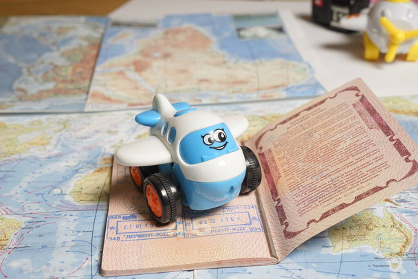 Маленький голубой игрушечный самолет, лежащий на странице паспорта с визовыми штампами на карте слов, тонизированный - Фото, изображение