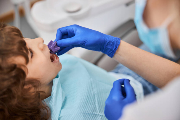 Pediatrinen hammaslääkäri, joka käyttää purenta lohkoa hoitaessaan lasta - Valokuva, kuva