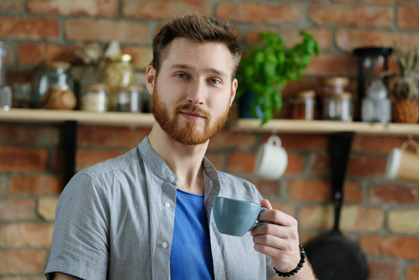 Schöner junger Mann mit Bart posiert auf der Küche - Foto, Bild