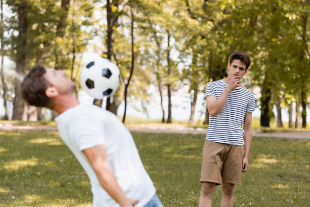 szelektív fókusz töprengő tinédzser fiú nézi apa focizni  - Fotó, kép