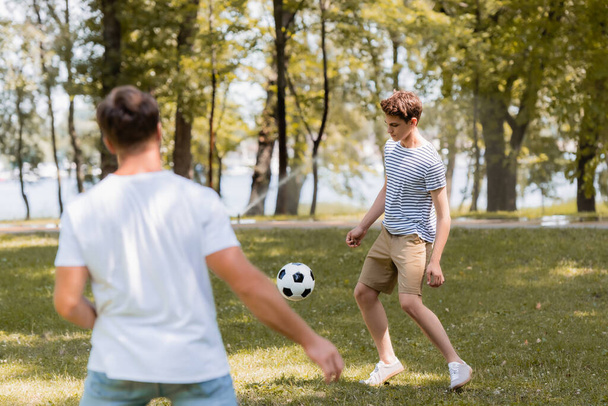selective focus of teenager boy playing football with father - Foto, Imagen