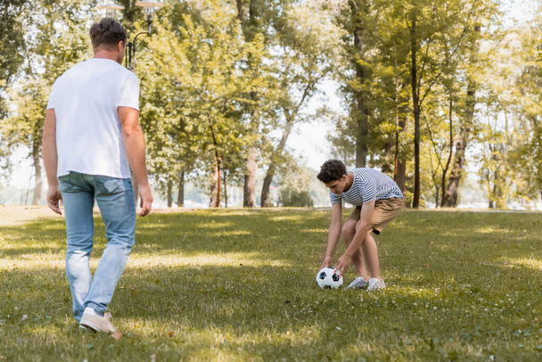 foyer sélectif de fils adolescent touchant le football près du père  - Photo, image
