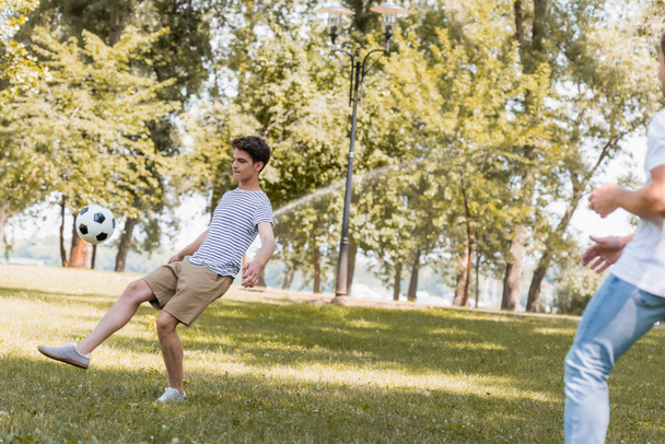 enfoque selectivo de hijo adolescente jugando al fútbol con el padre en el parque  - Foto, imagen