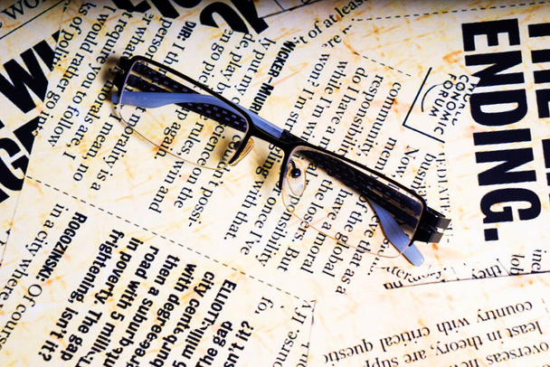 οπτικά γυαλιά βρίσκονται στην εφημερίδα με αγγλικές γραμματοσειρές, τονισμένα - Φωτογραφία, εικόνα