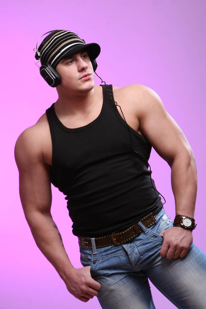 Молодий і сильний культурист з навушниками на фіолетовому фоні
 - Фото, зображення