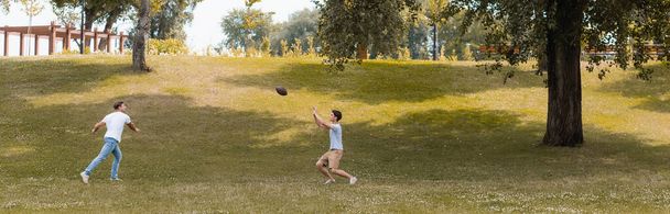 заголовок сайта отца и сына-подростка, играющего в американский футбол в зеленом парке  - Фото, изображение